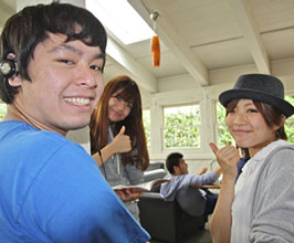 Japanese students in class giving thumbs up and smiling. 